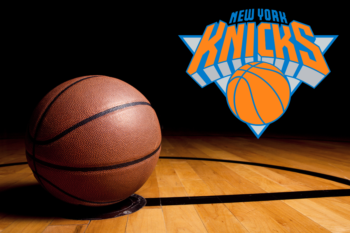 A basketball resting on a wooden court under a spotlight, with the New York Knicks logo displayed prominently in the background.