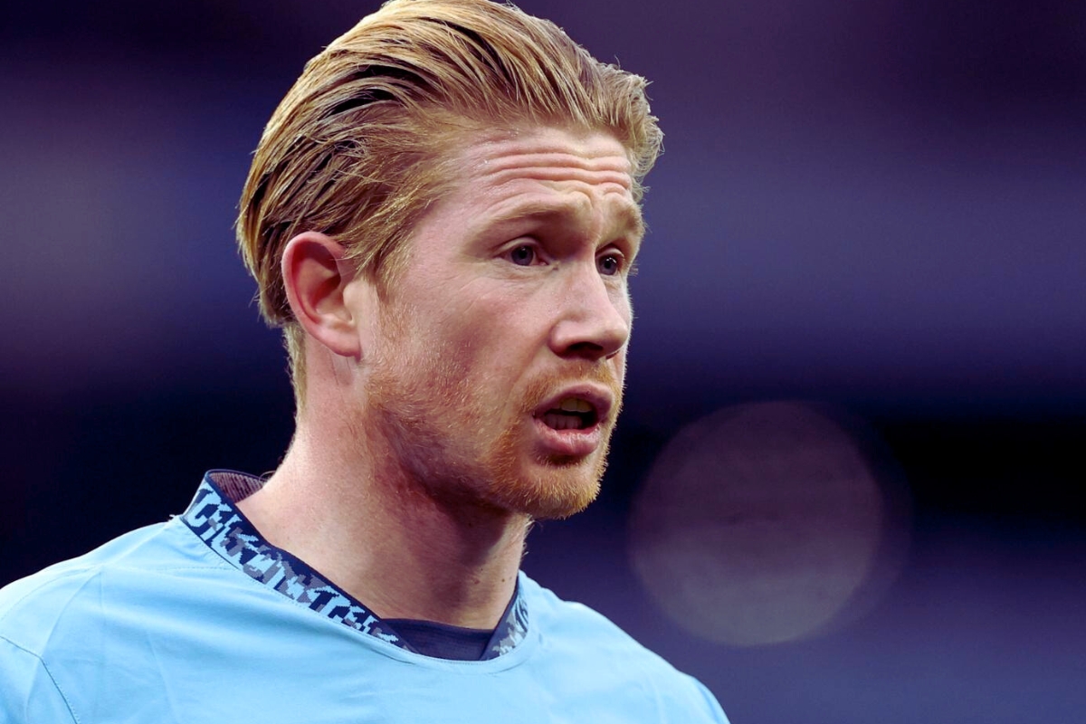 A close-up of a soccer player, Kevin De Bruyne, wearing a light blue jersey, with a focused expression during a match.