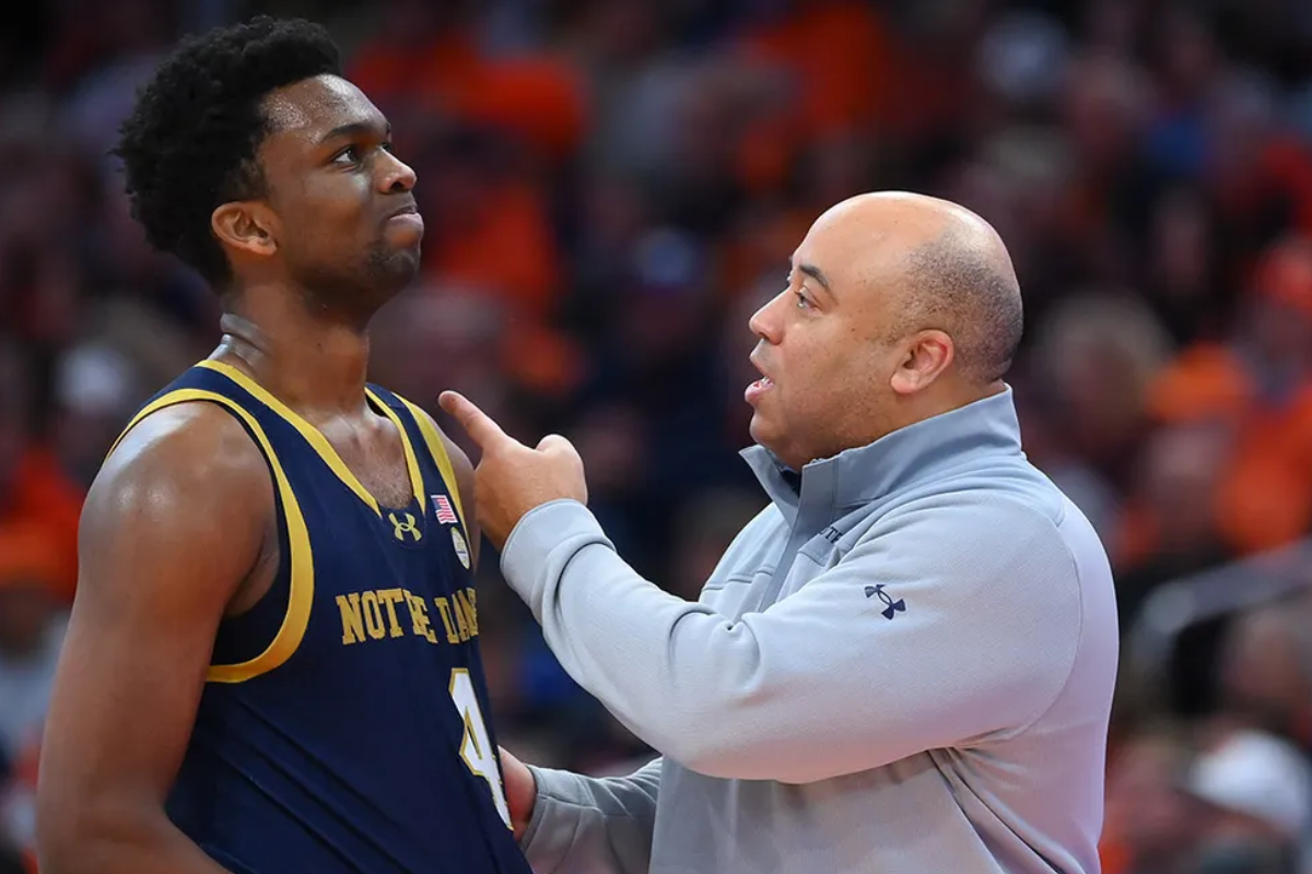 Notre Dame basketball coach gives instructions to a player during a game.